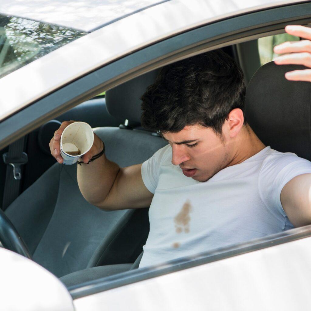Man in car spilling coffee on shirt